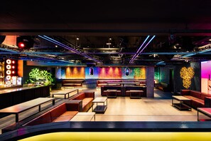 Un bar moderno con luci al neon, sedute in pelle e postazione per il DJ.