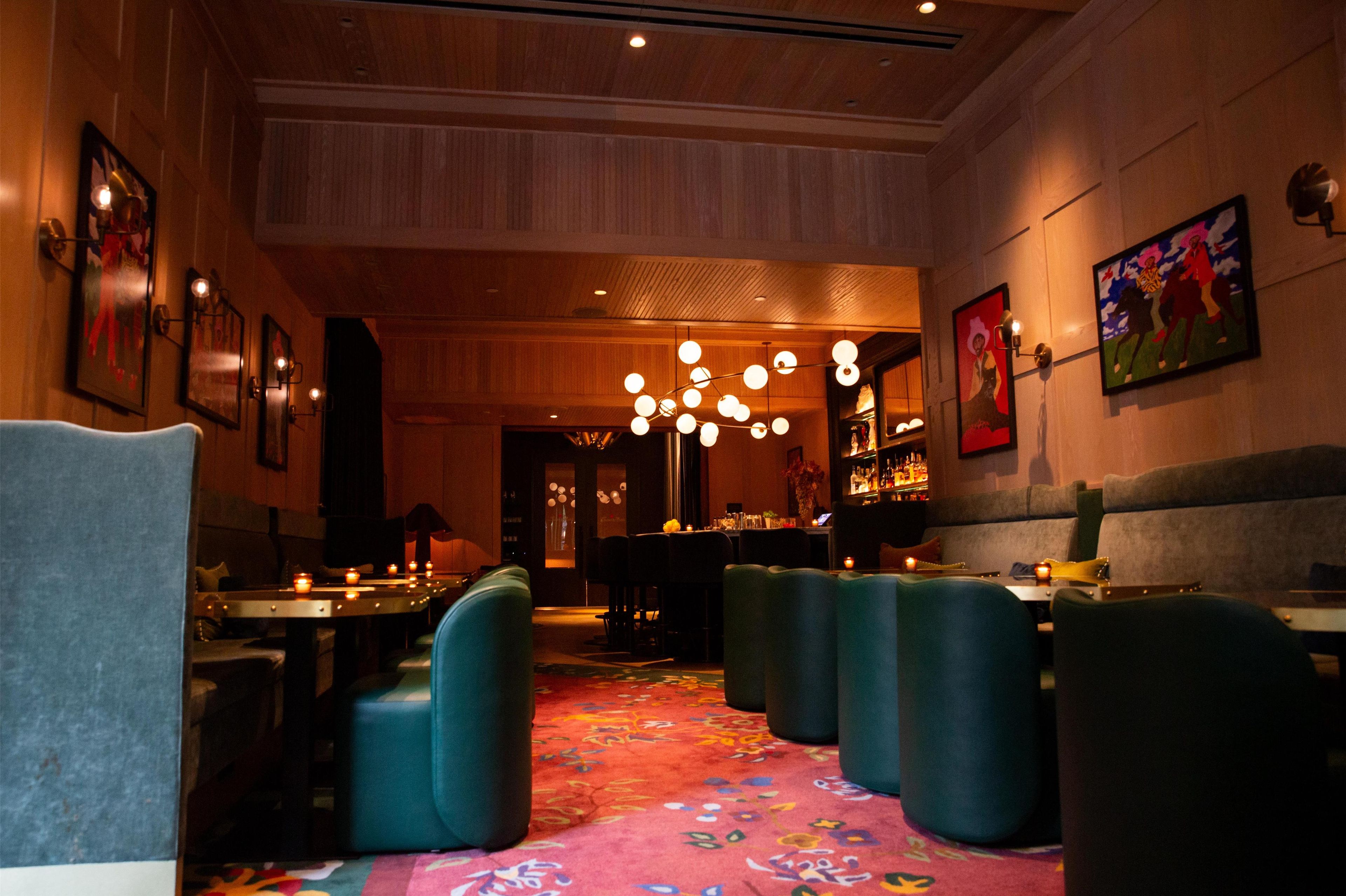 L’intérieur d’un restaurant, avec des banquettes, des tables et un coin bar.