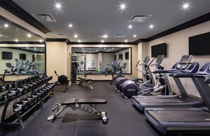 Ein Fitnessstudio mit Laufbändern, Kraftgeräten und Kurzhanteln.