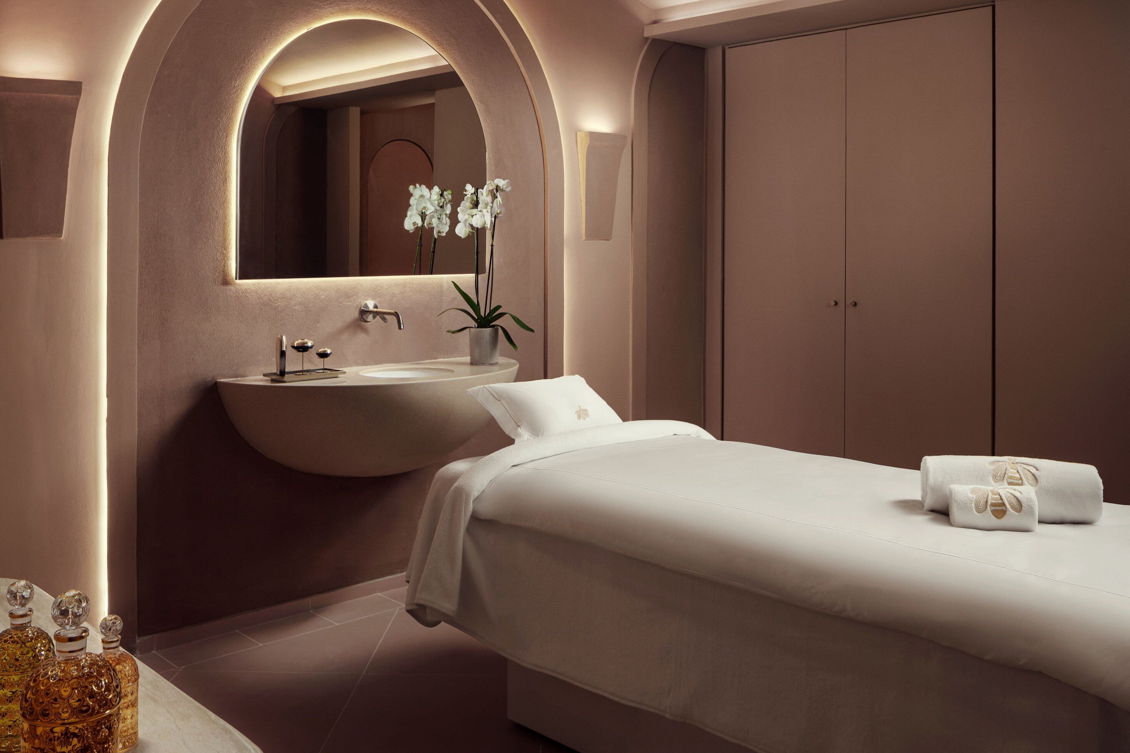 A modern bedroom with a large bed, a built-in sink, and a mirror above the sink.