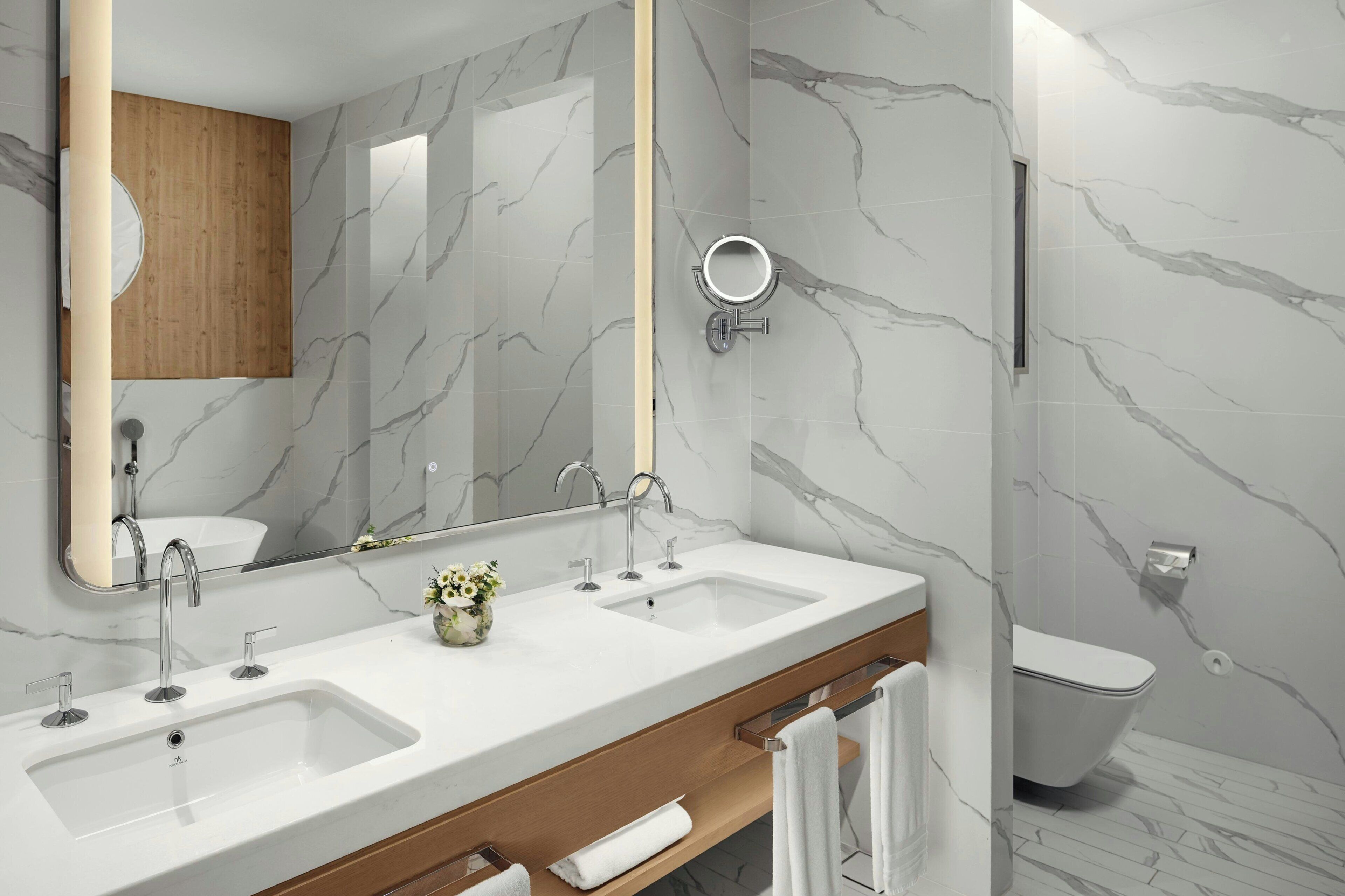 A modern bathroom with two sinks, a large mirror, and a toilet.