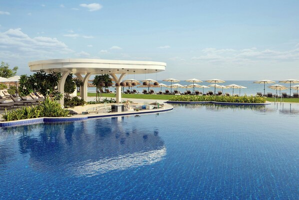 A pool area with lounge chairs and umbrellas, a covered seating area, and a view of the ocean. - The St. Regis Al Mouj Muscat Resort (Muscat)