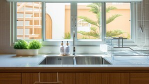Una cocina con un ventanal grande, un fregadero y un dispensador de jabón para lavar platos.