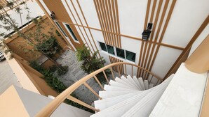 Una escalera de caracol con barandilla de madera y peldaños blancos, que conduce a una pared blanca con listones de madera verticales y un ventanal.