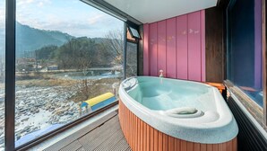 Une salle de bain moderne avec un jacuzzi, de grandes fenêtres et une vue sur un paysage enneigé.