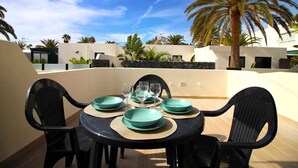 An outdoor dining area with a round table, black chairs, and teal plates.