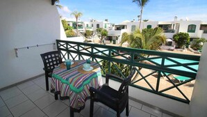 A balcony with a table and chairs, overlooking a swimming pool and a residential area. - Nautic Apartment in Puerto del Carmen (Puerto Del Carmen)