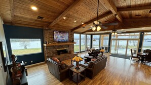 A spacious living room with a fireplace, leather sofas, and a large TV screen.
