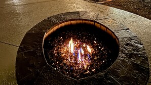 A fire pit area with a wooden pergola structure and outdoor seating.