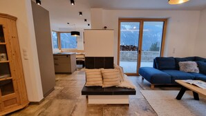 A modern living room with a sofa, a coffee table, and a dining area with a kitchen in the background. - Home Dachsbau by Interhome (See)