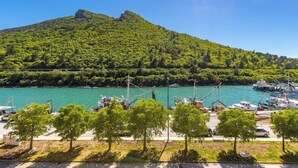 Un port de plaisance avec des bateaux amarrés, un ciel dégagé et, au loin, une colline couverte d’une végétation luxuriante.