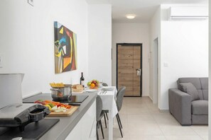 Une cuisine moderne avec un coin repas, un canapé gris et une porte en bois.