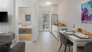 A modern apartment with a dining area, kitchenette, and a TV mounted on the wall. - Sea-View Balcony Apt Lady Laura, Plomin, Croatia (Plomin)