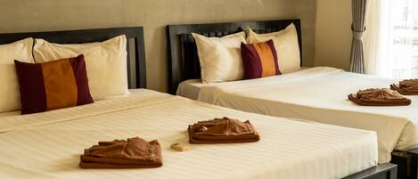 A hotel room with two beds, each with a headboard, pillows, and folded towels.