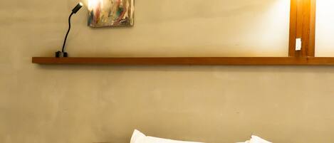 Une chambre d’hôtel avec un lit soigneusement fait, un tableau accroché au mur et une lampe sur une table de chevet.