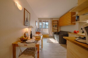 Een ruimtelijk ingerichte leefruimte met een eethoek, kitchenette en een bank.
