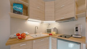 A modern kitchen with wooden cabinets, a sink, a microwave, and a coffee machine. - Cham Sud Genévrier104 sleeps 2 next Aiguille du Midi, Chamonix, France (Chamonix)