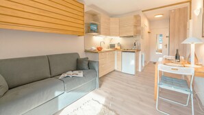 A modern apartment with a grey sofa, a small dining table, and a kitchenette. - Cham Sud Genévrier104 sleeps 2 next Aiguille du Midi, Chamonix, France (Chamonix)