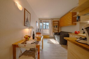 A compact living space with a dining area, kitchenette, and a sofa.