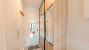 A hallway with a wooden floor, a glass door, and a small rug. - Cham Sud Genévrier104 sleeps 2 next Aiguille du Midi, Chamonix, France (Chamonix)