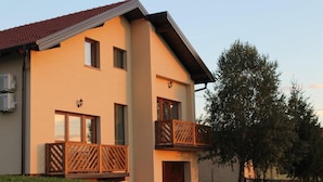 A two-story building with a flat roof, a balcony with wooden railings, and a small porch. - Agrotourism Vinia (Bjelovar)