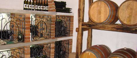 A wine cellar with wooden barrels and metal racks holding wine bottles.