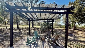 Un espace extérieur abrité, aménagé avec des chaises et une table, et entouré d’arbres.
