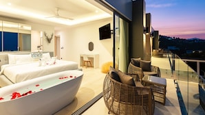 A modern bedroom with a large bed, a bathtub with rose petals, a desk, and a balcony with wicker furniture. - Luxury 5 Bedroom Modern Villa - KBR17 (Koh Samui)
