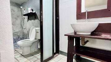 A bathroom with a toilet, shower, and sink.