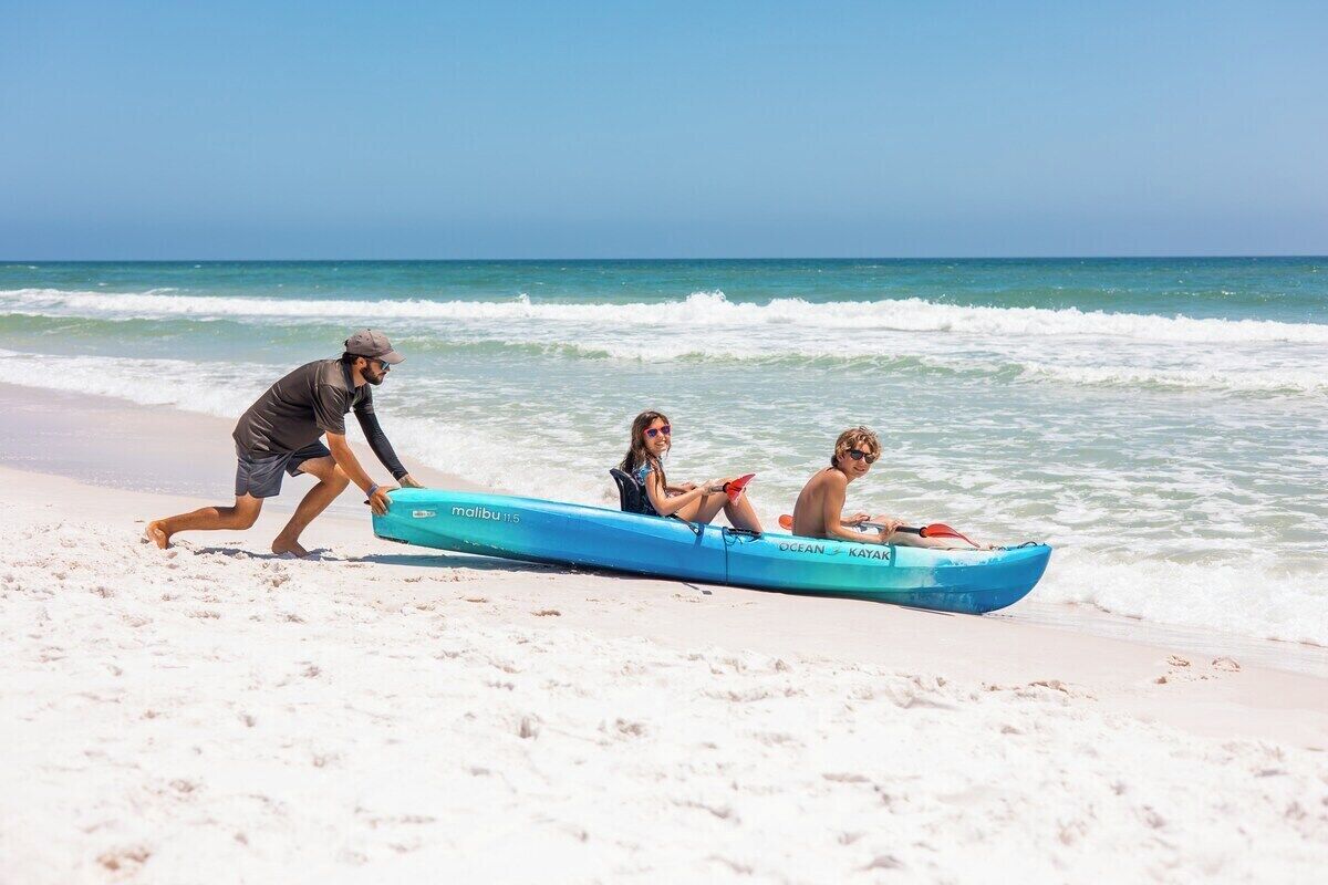 A beach scene with a kayak on the sand and the ocean in the background.