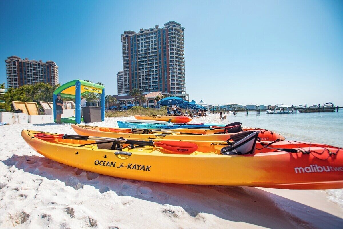 Une plage avec des kayaks, un poste de surveillance des sauveteurs et, en arrière-plan, des immeubles de grande hauteur.