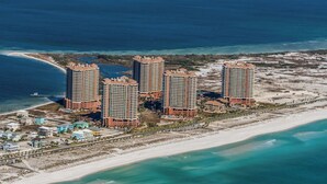 Un complexe hôtelier situé sur la côte, composé de plusieurs immeubles de grande hauteur, offrant un accès direct à la plage et doté d’une plage de sable.