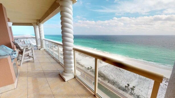 Un balcon avec vue sur la plage, une balustrade et des chaises longues.
