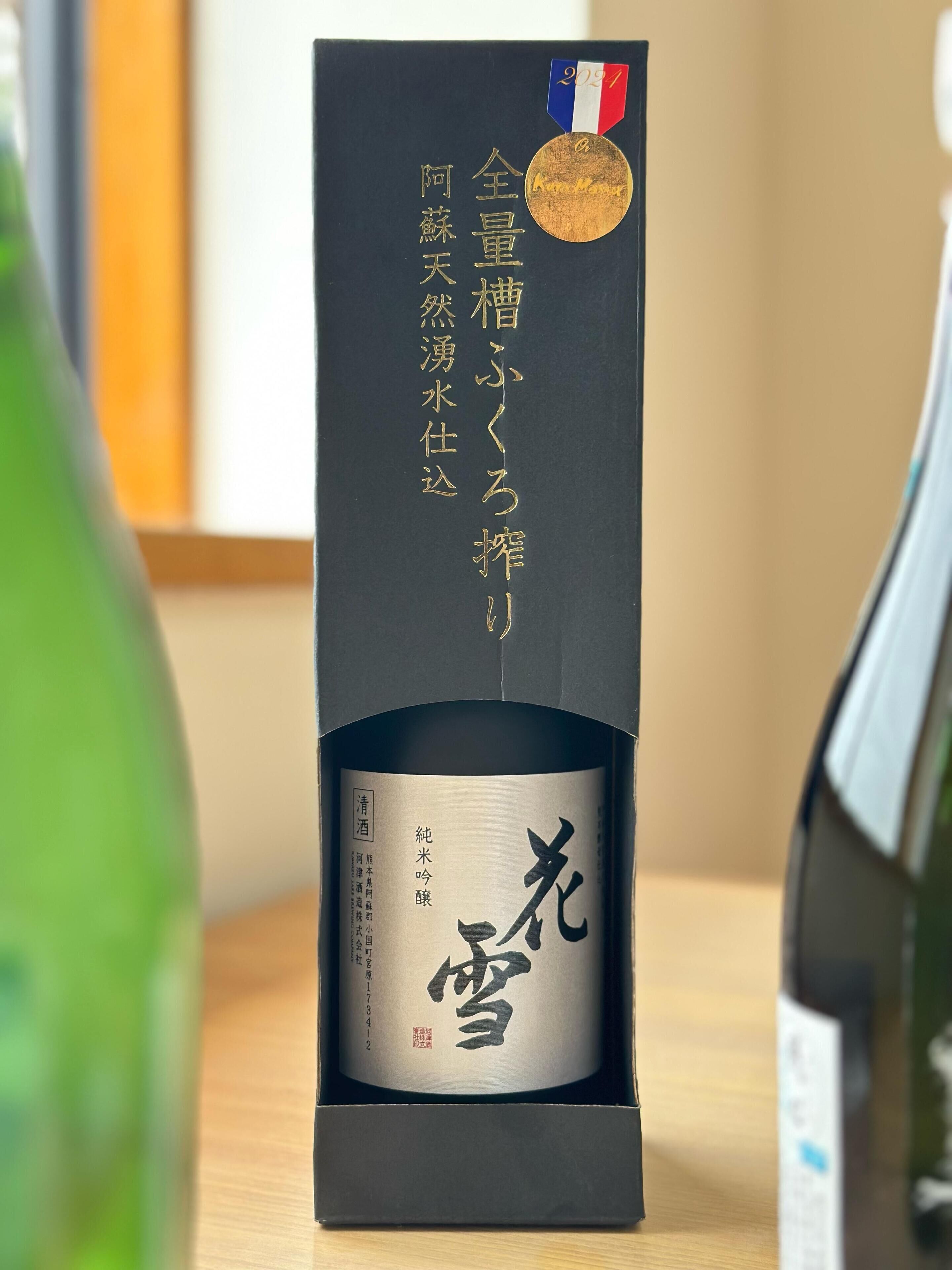 A bottle of sake with a medal on top, placed in a black box.