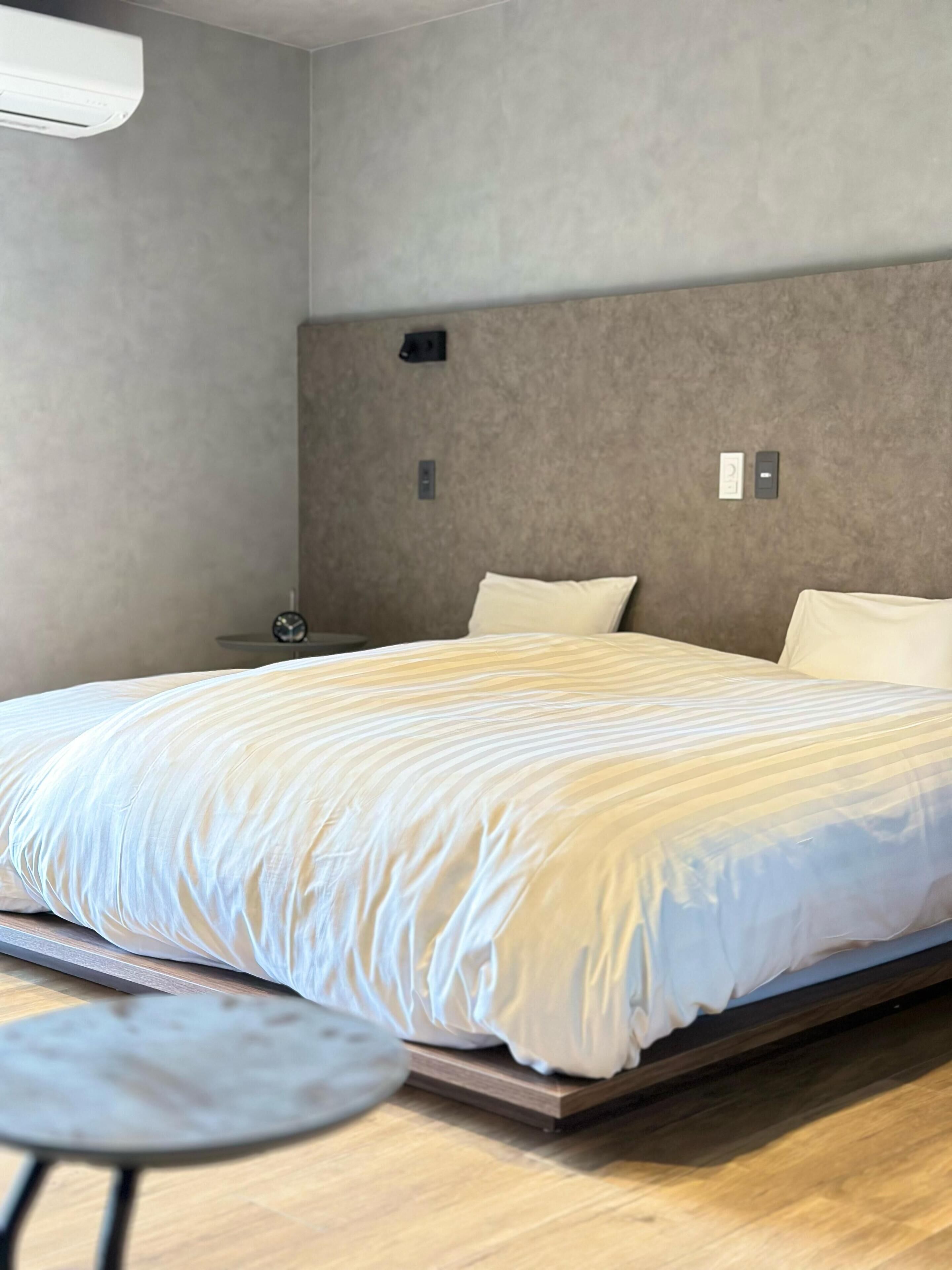 Une chambre à coucher moderne avec un grand lit, une table de chevet et une petite table ronde.