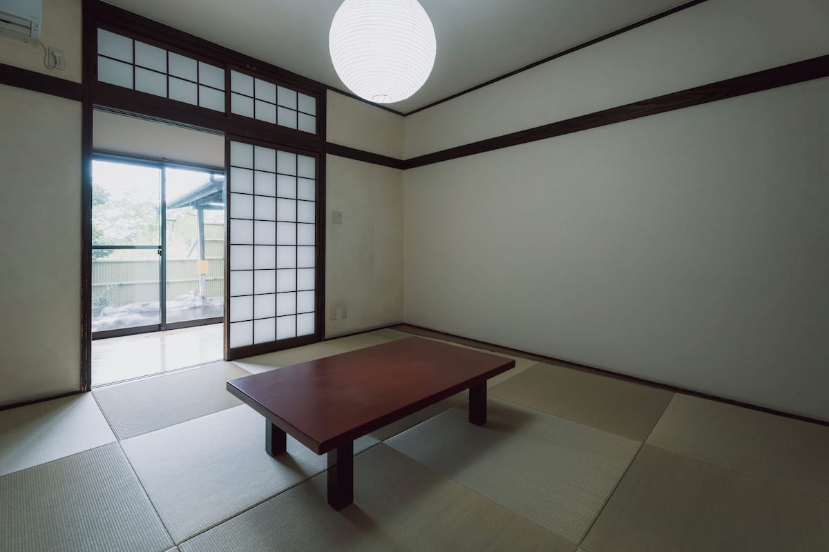 Une pièce de style japonais traditionnel, avec un sol recouvert de tatamis, une porte coulissante et une table en bois.