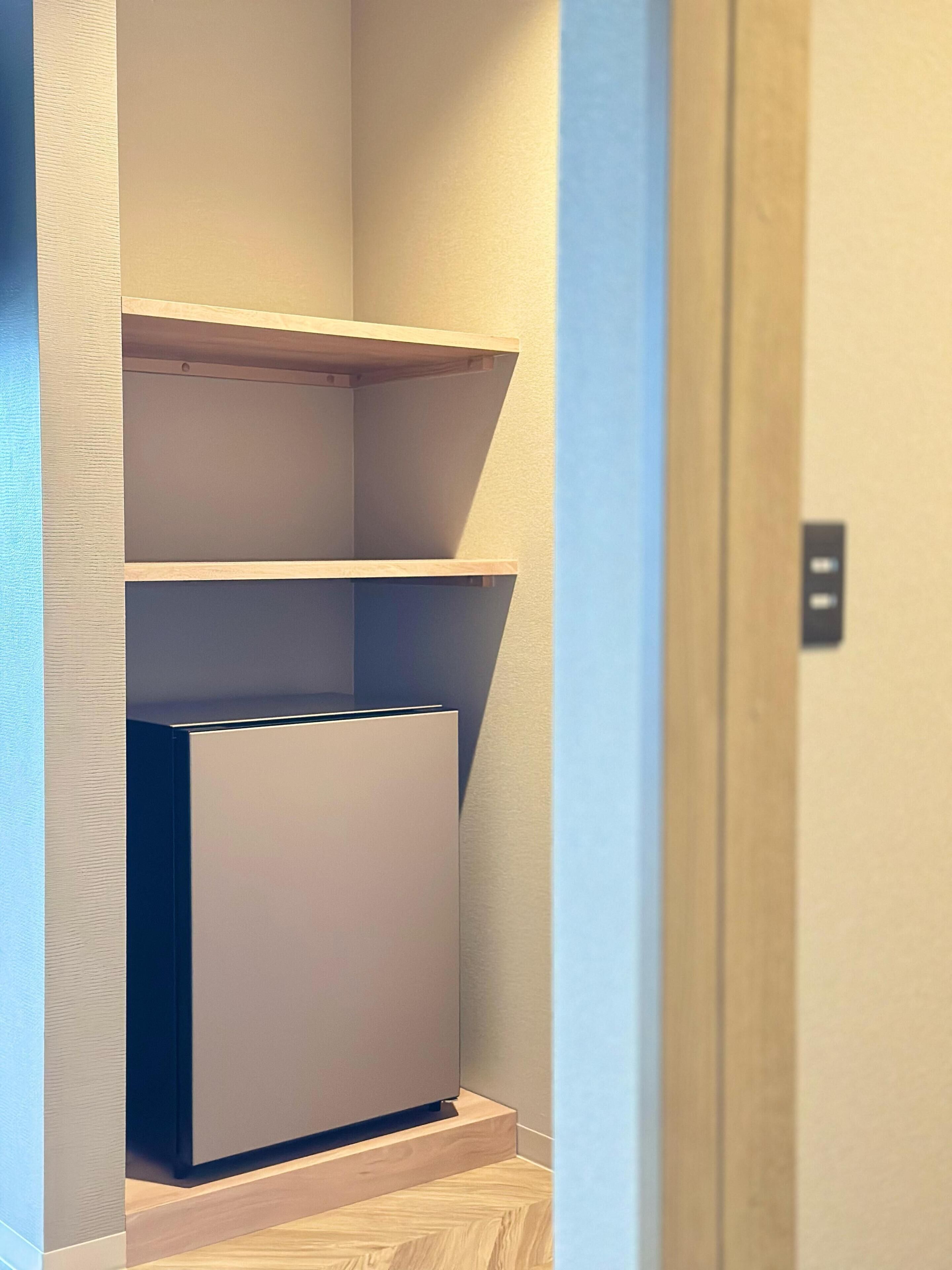 A narrow hallway with a built-in shelving unit and a door at the end.
