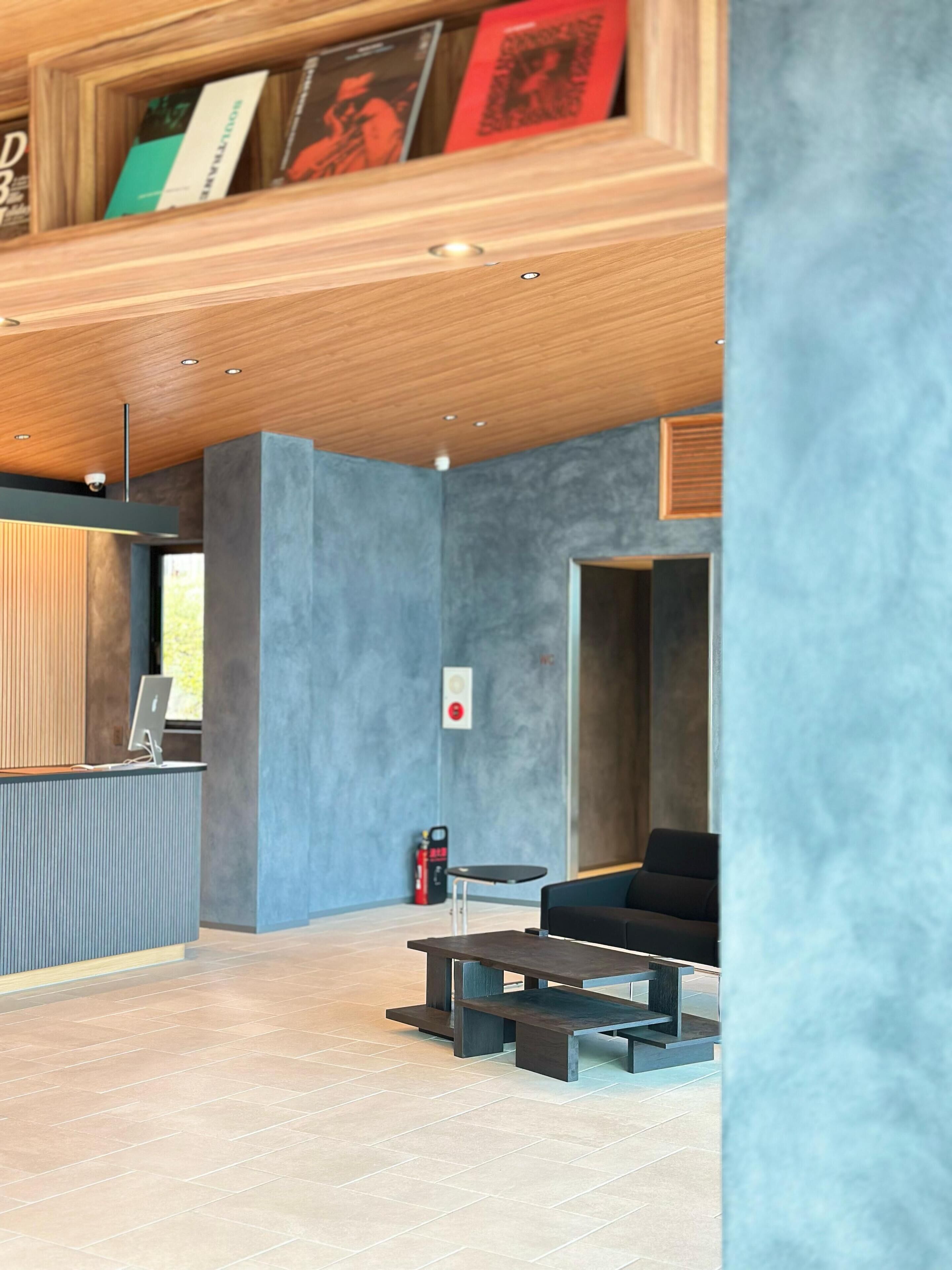 A modern interior with a reception desk, seating area, and a bookcase.