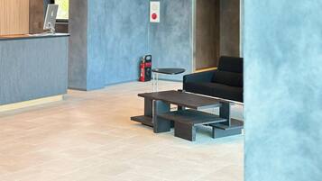 A modern interior with a reception desk, seating area, and a bookcase.