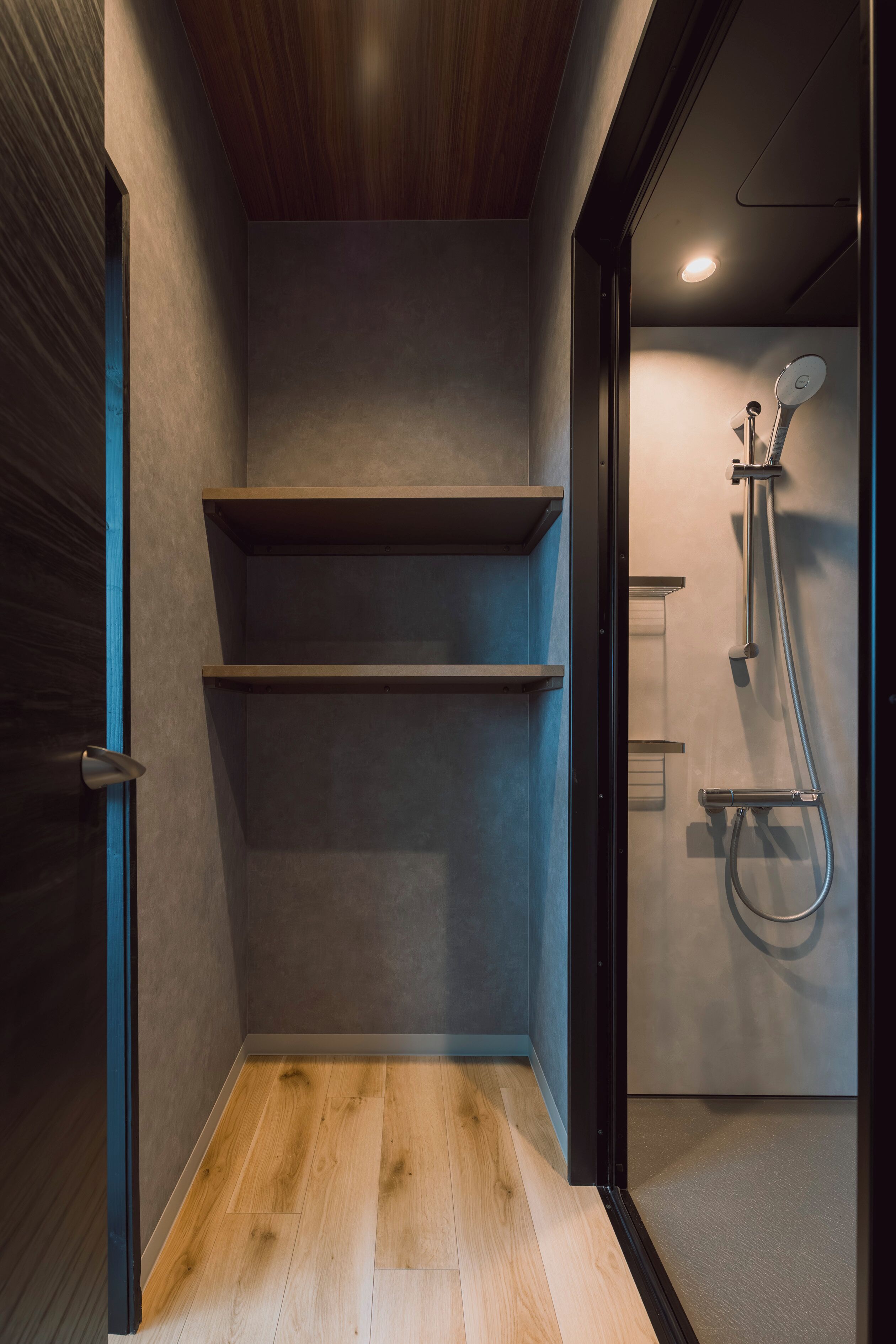 A modern bathroom with a shower, wooden shelves, and a wooden floor.