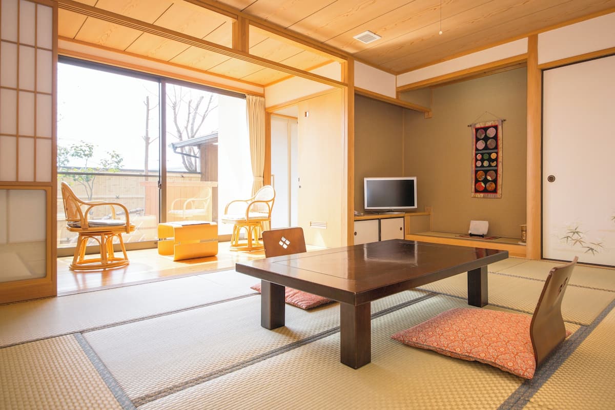 Une pièce de style japonais traditionnel, avec un sol recouvert de tatamis, une table basse et un téléviseur.
