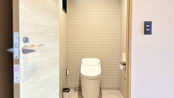 A compact bathroom with a toilet, a trash bin, and a pair of slippers on the floor.