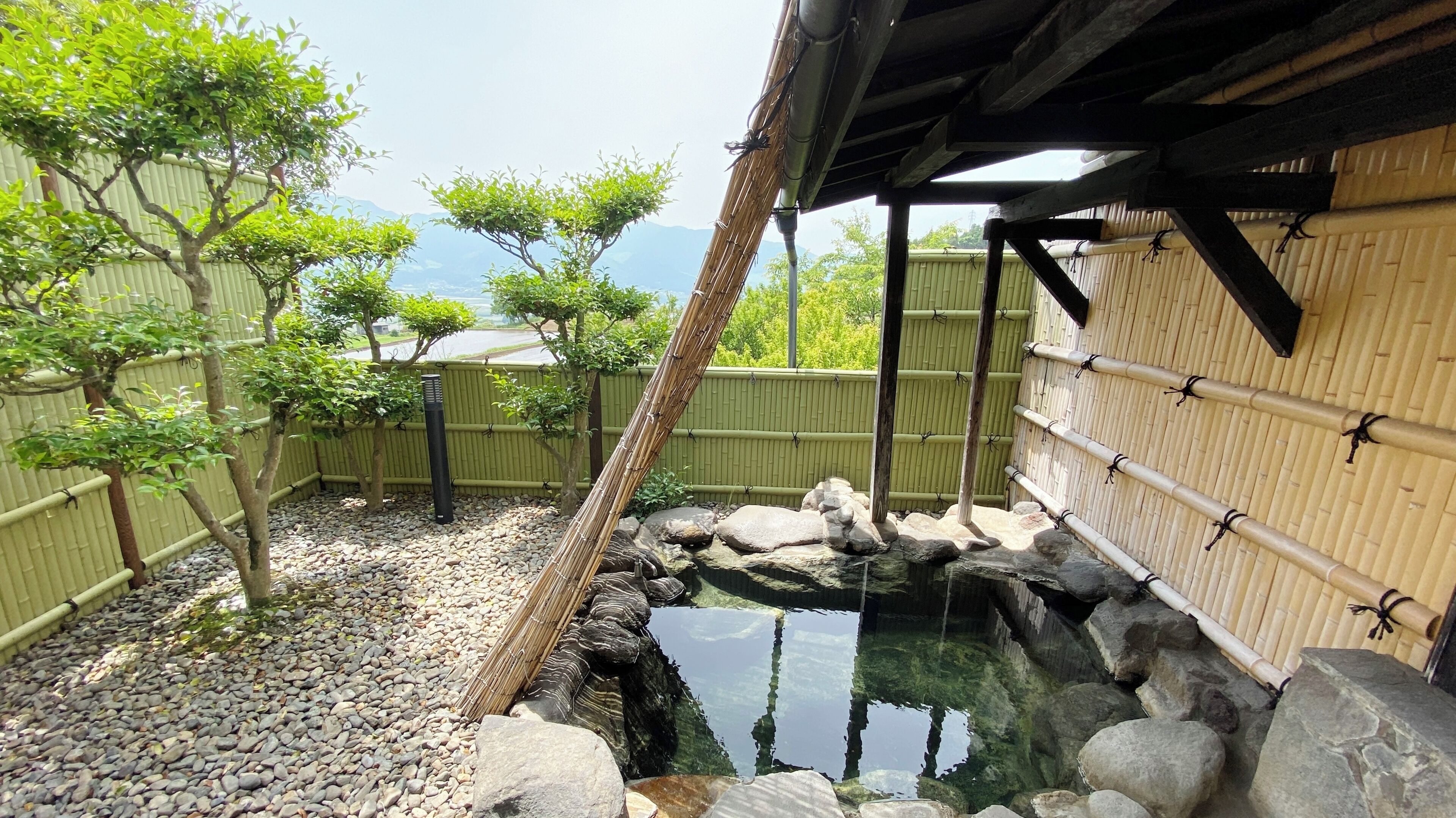 A traditional Japanese garden with a koi pond, bamboo fences, and a wooden structure.