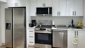 A modern kitchen with white cabinets, stainless steel appliances including a refrigerator, microwave, oven, and dishwasher, and a marble backsplash. - Bright 2BR unit | Free Parking | Family Friendly | Richmond Hill (Richmond Hill)