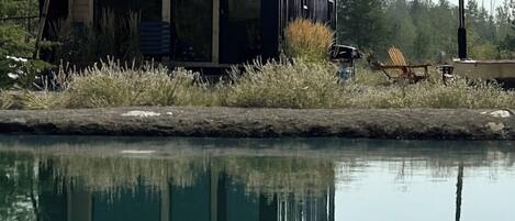 A modern house with large windows and a reflection in the water.