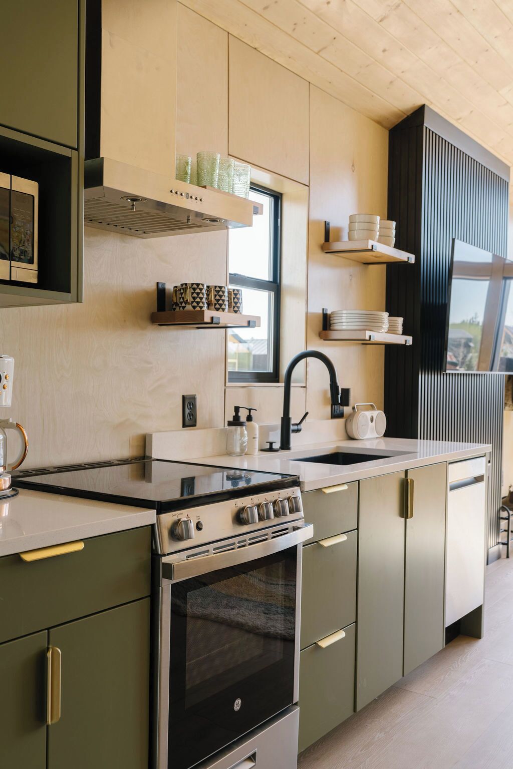 A modern kitchen with a built-in stove, oven, and sink. There are wooden cabinets and a window providing natural light.