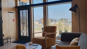A spacious room with large windows, a wooden ceiling, and a cozy seating area with a sofa and armchairs. - Yellowstone Peaks Hotel (Island Park)