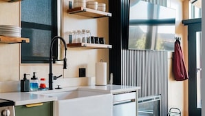 Et moderne køkken med indbygget ovn, opvaskemaskine og et stort vindue.
