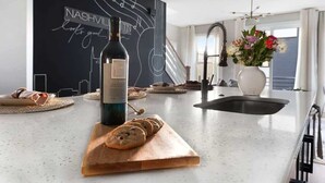 Une cuisine moderne avec un mur recouvert d’une peinture ardoise, une bouteille de vin et une planche à découper avec du pain.