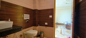 A bathroom with a sink, toilet, and a sign instructing not to flush toilet paper. - The Unmad (Dharamshala)